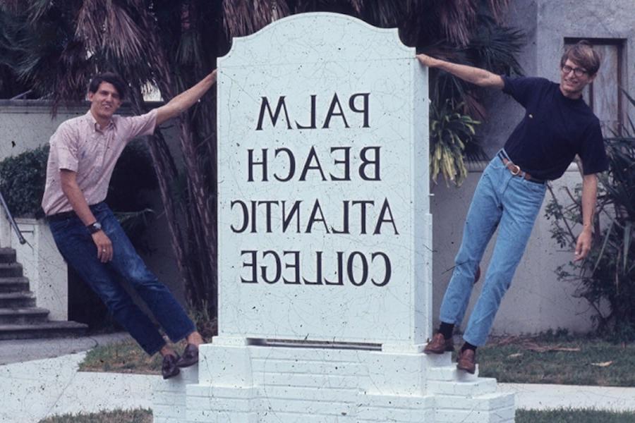 Two male posing next to college signage in the early days of Palm Beach Atlantic College